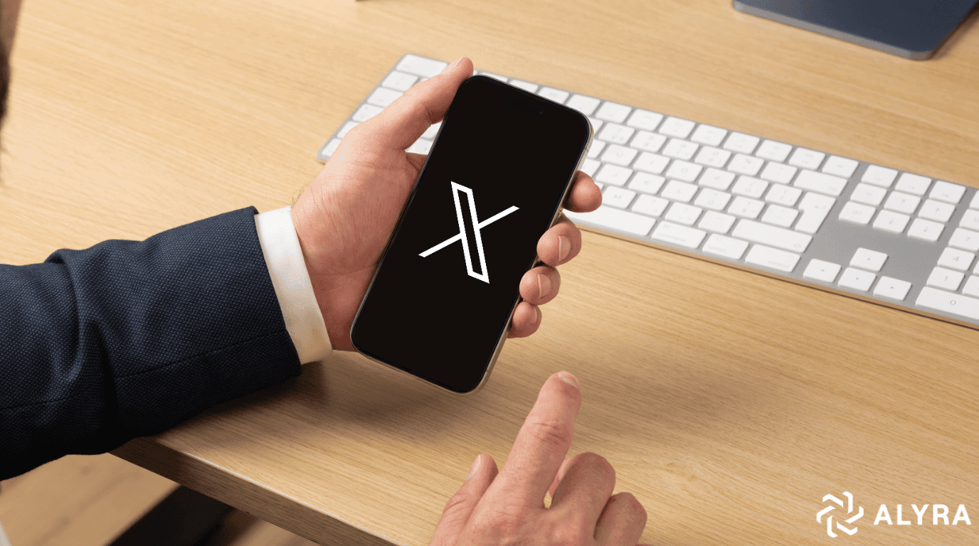 Homme tenant un téléphone avec le logo X s'affichant